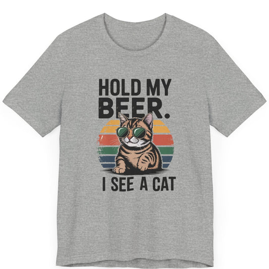 a vintage look with a cat with sunglasses on. The words are hold my beer. i see a cat